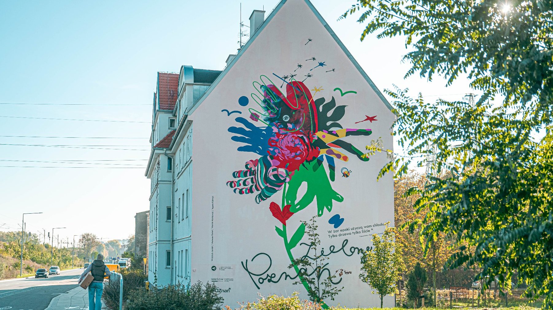 Na zdjęciu kamienica, na jej bocznej ścianie kolorowy mural - splecione dłonie