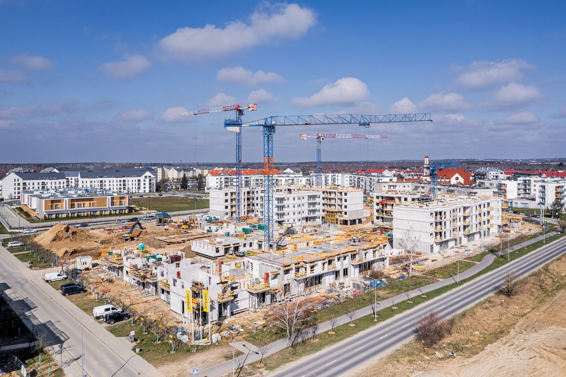 Zdjęcie z lotu ptaka przedstawia plac budowy, nad którym górują dzwigi. - grafika artykułu