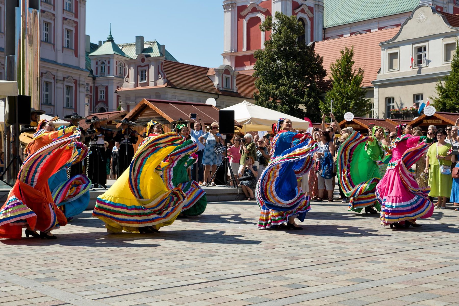 Zdjęcie z zeszłorocznej edycji Festiwalu dobrego Smaku. Na pierwszym planie tańczące kobiety w kolorowych strojach - grafika artykułu