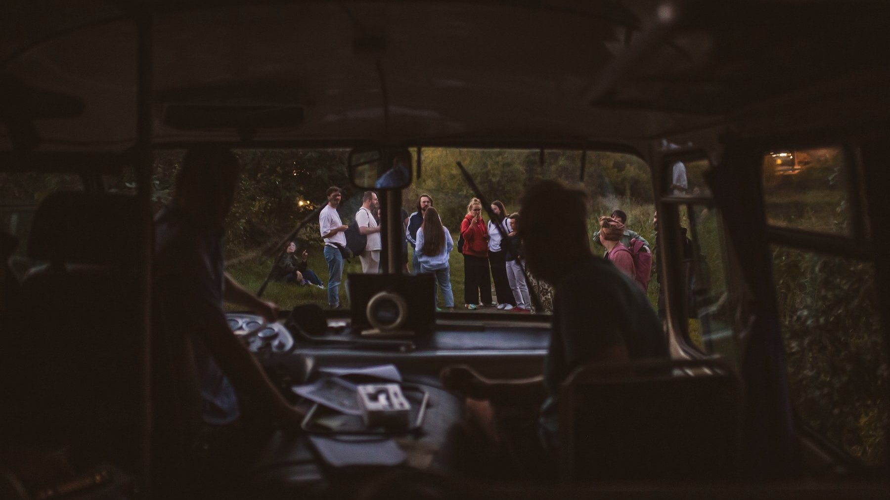 Zdjęcie przedstawia ludzi widzianych z okna autobusu.