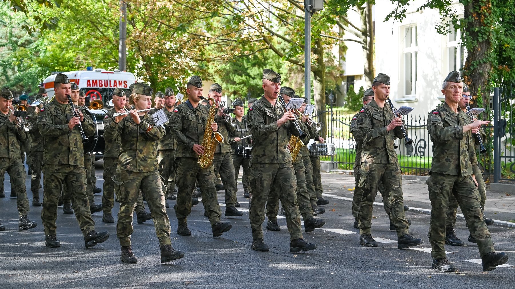 Zdjęcie przedstawia orkiestrę wojskową idącą ulicą.