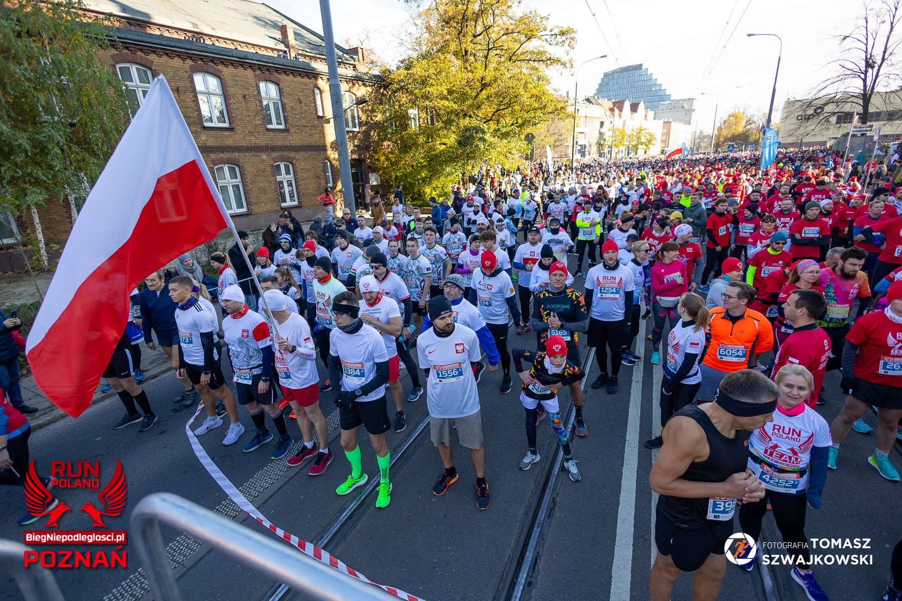 Bieg Niepodległości 2023, fot. Tomasz Szwajkowski - zawodnicy stoją na starcie w białych i czerwonych koszulkach - grafika artykułu