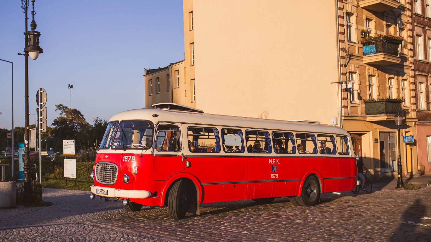 Zdjęcie przedstawia czerwony zabytkowy autobus.