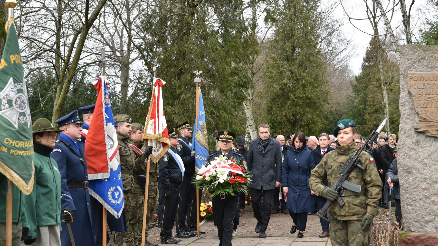 Zdjęcie przedstawia osoby skłądające kwiaty.