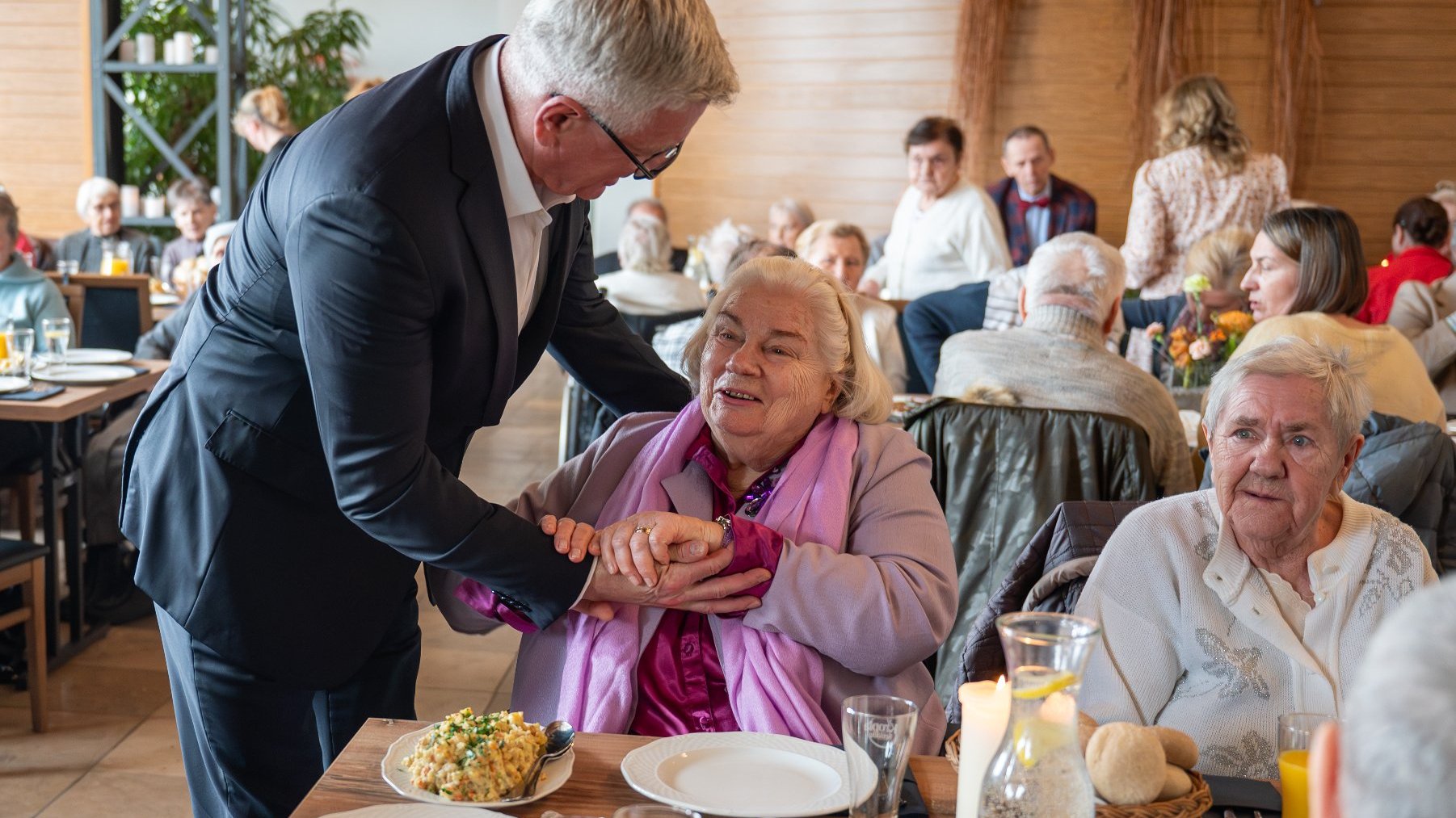 Na zdjęciu prezydent Poznania rozmawiający z siedzącą przy stole kobietą