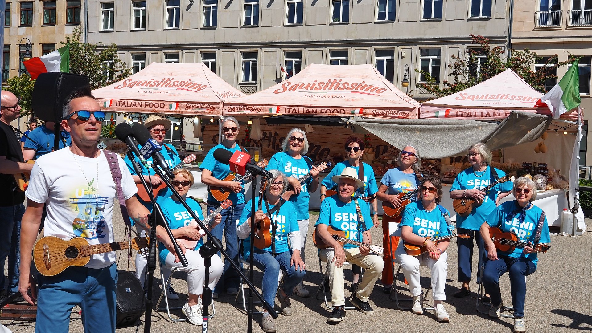 Na zdjęciu zespół seniorów w niebieskich koszulkach, każdy ma ukulele w ręku - grafika artykułu