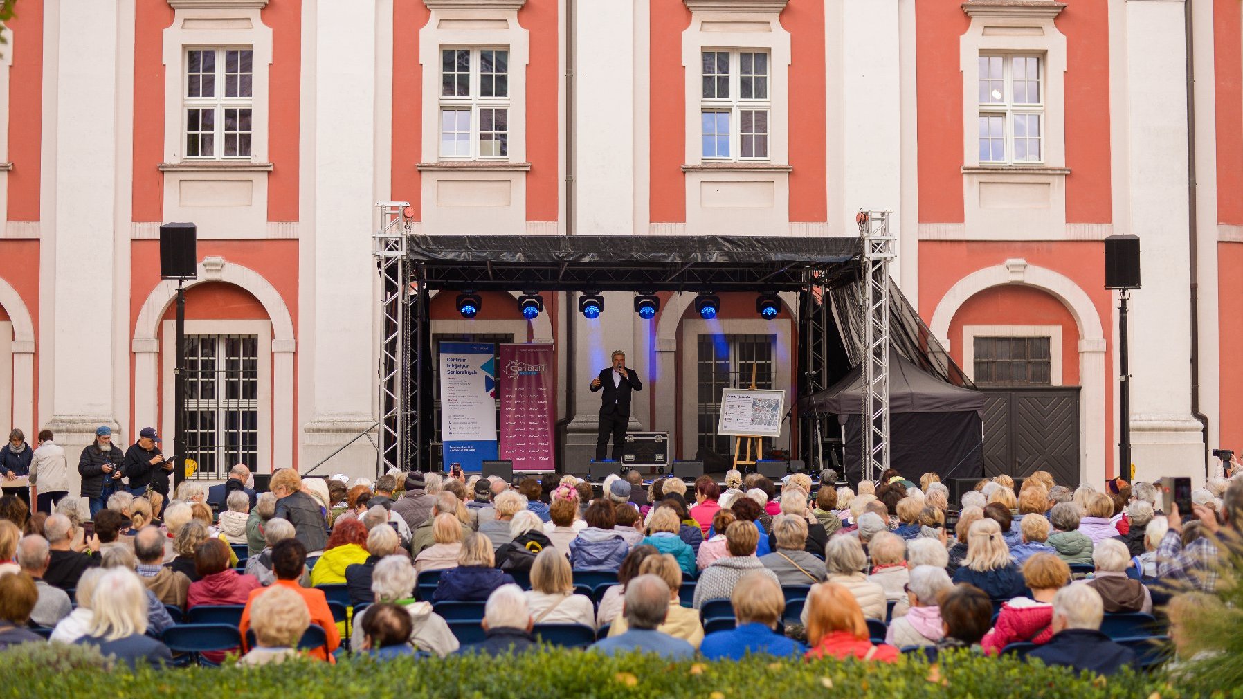 Na zdjęciu tłum seniorów, słuchających śpiewaka na scenie