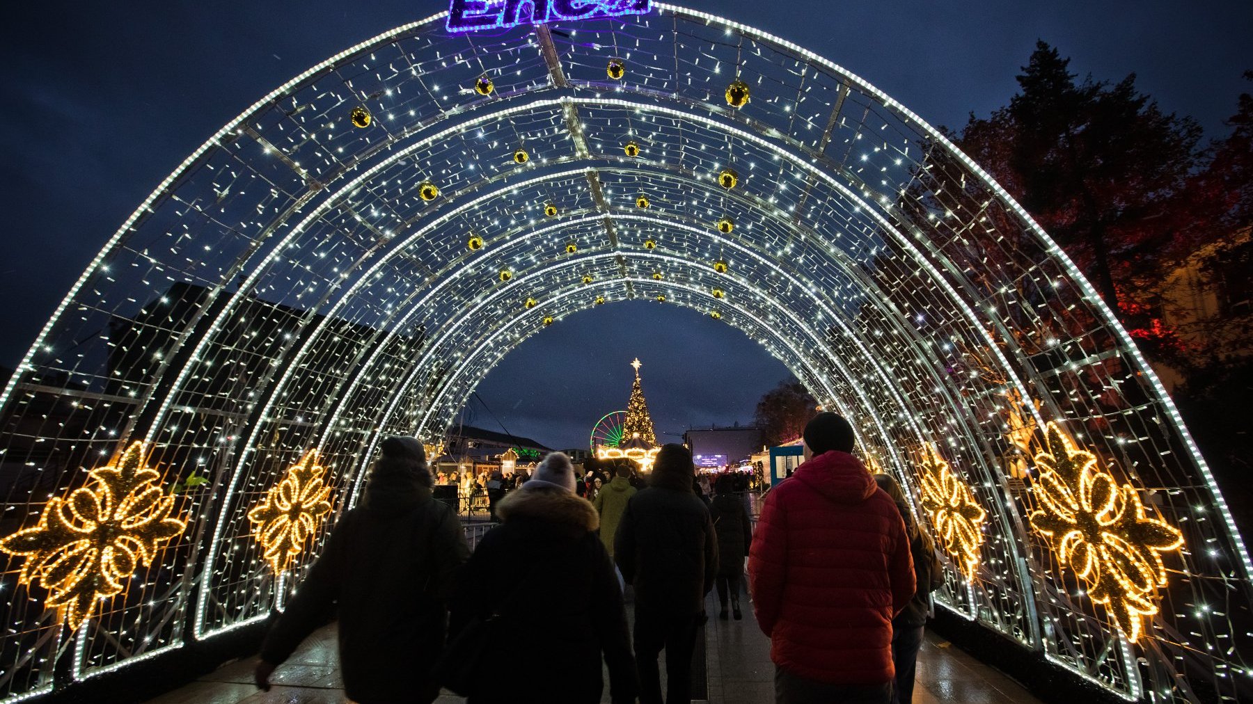 Zdjęcie przedstawia rozświetlony łuk, pod którym przechodzą ludzie.