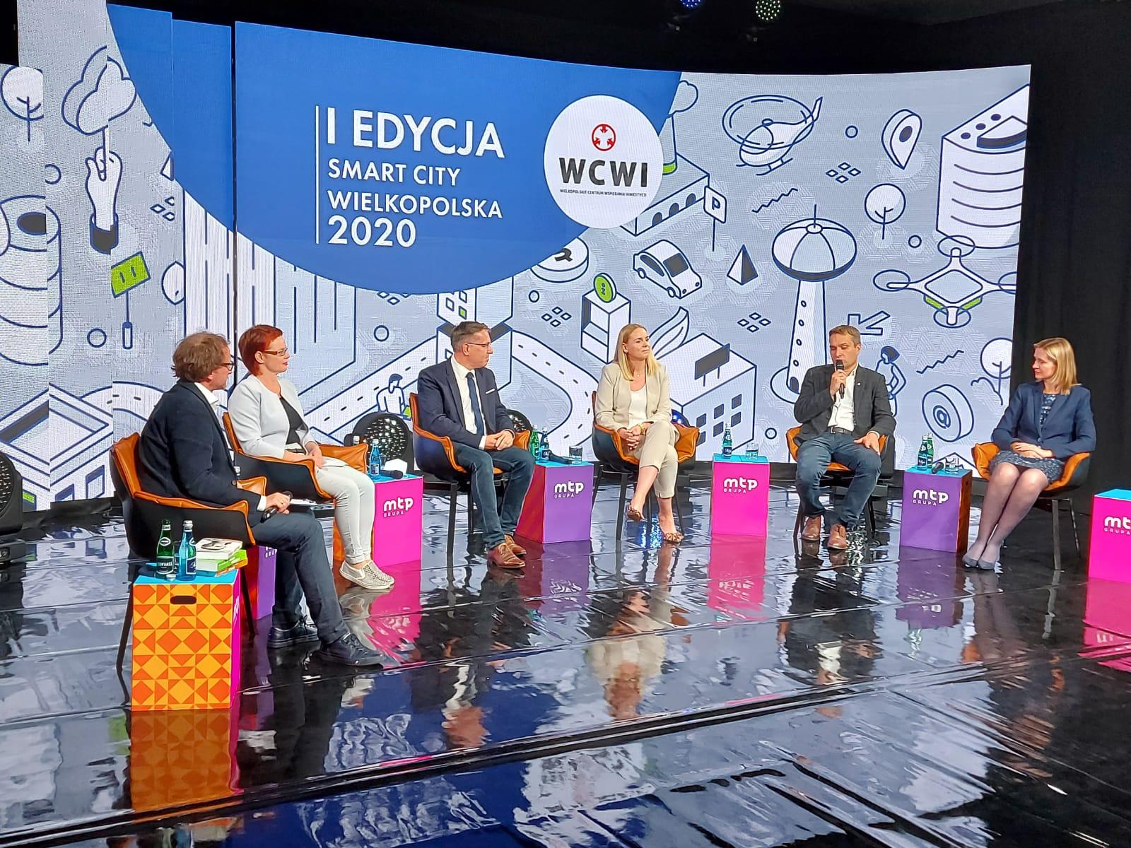 The image shows three men and three women sitting and talking to each other using a microphone