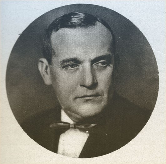 Zdjęcie portretowe Mieczysława Palucha, ubranego w marynarkę i koszulę z muchą u kołnierzyka.