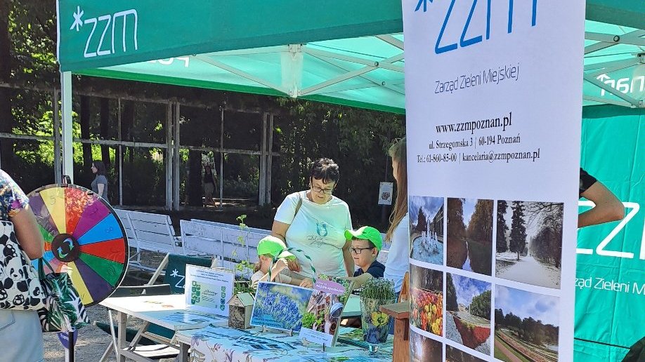 akcje edukacyjne - relacja z zielonych warsztatów w ramach "Akademii Zielony Poznań" - "Zieloni od 30 lat - jubileusz z klimatem" - 25 maja 2024 r. Park Wilsona,stoisko edukacyjne Zarządu Zieleni Miejskiej. uczestnicy mieli możliwość wzięcia udziału w quizie i wygrania gadżetów ZZM czy mini zestawu narzędzi ogrodniczych, na zdjęciu widoczne dzieci biorące udział w quizie.