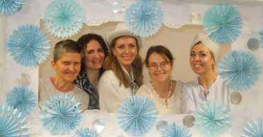 pięć kobiet pozujących do zdjęcia w biało- niebieskiej ramie z papieru