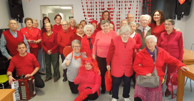 grupa kilkudziesięciu seniorów i pracowników ubranych na czerwono pozuje do zdjęcia