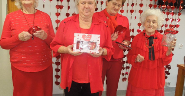cztery kobiety ubrane na czerwono stoją na tle czerwonej girlandy, w rękach trzymają nagrody