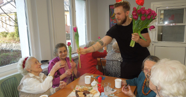 młody mężczyzna wręcza starszym kobietom tulipany