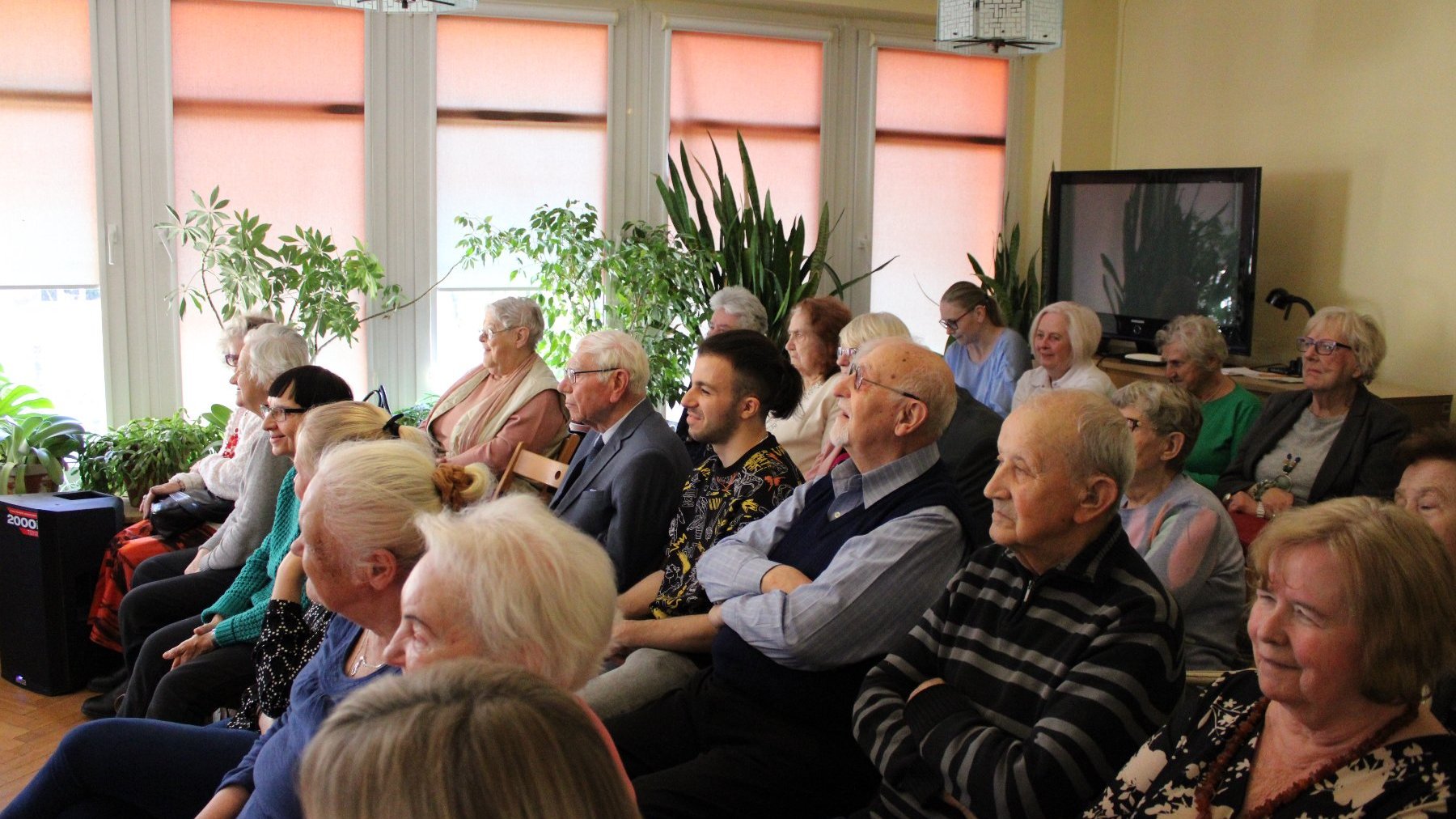 Na zdjęciu widać dużą grupę seniorów oglądających sztukę