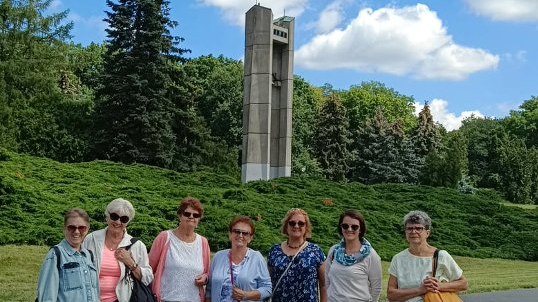 Siedem kobiet w stojących w parku na tle pomnika