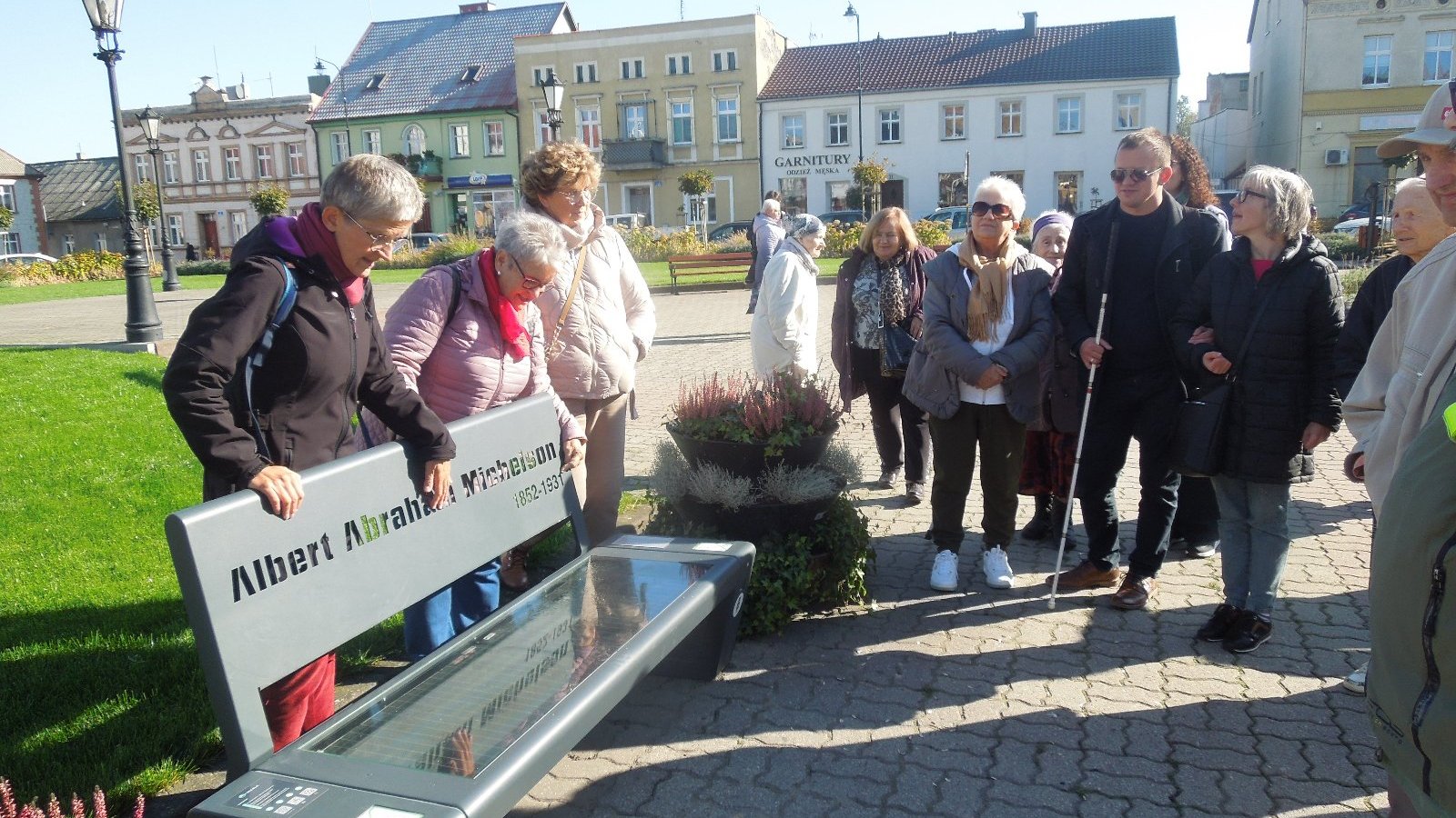 grupa osób stoi wokół ławki z napisem "Albert Abraham Michelson"