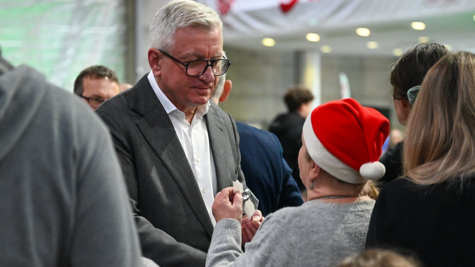 Na zdjeciuy prezydent Poznania łamiący się opłatkiem z kobietą w czapce mikołaja