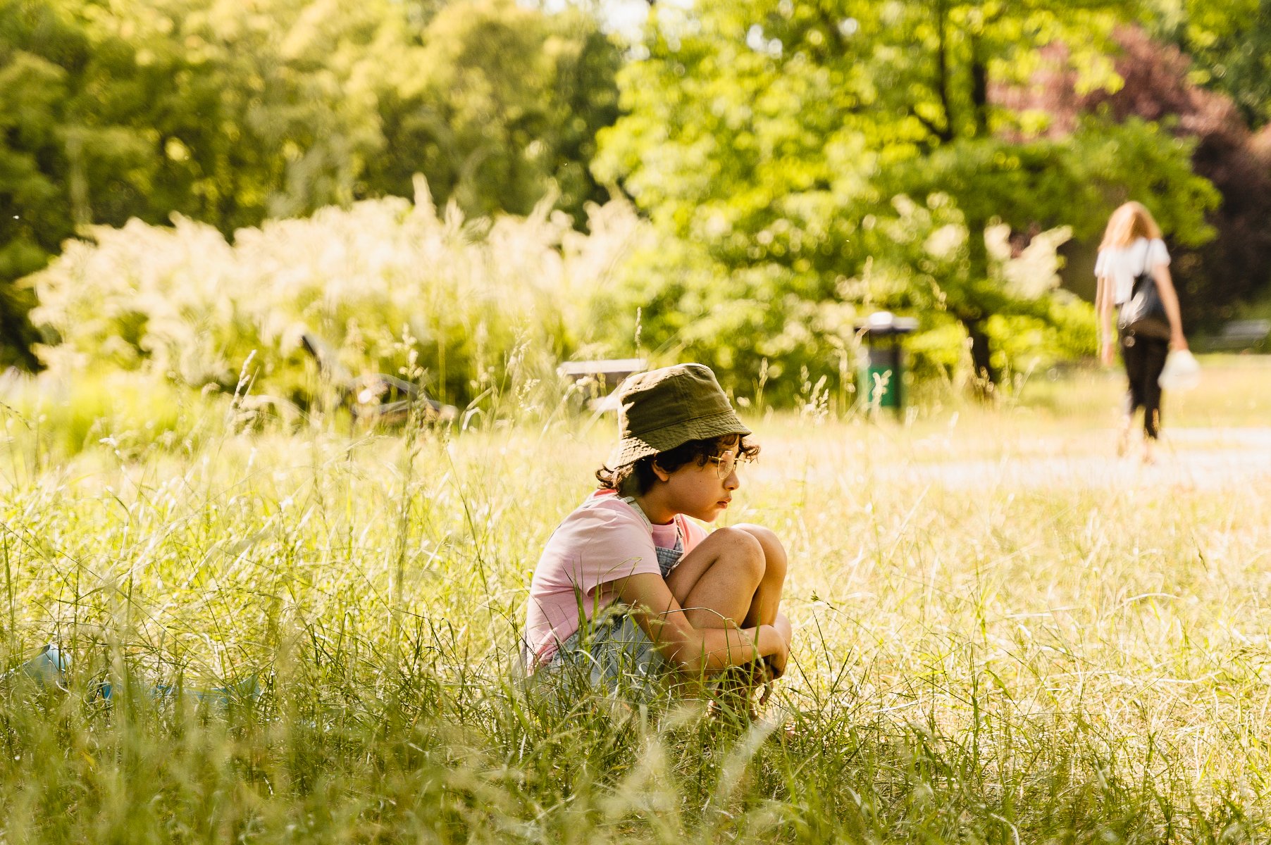 dziewczynka siedząca samotnie na trawie w parku - grafika artykułu