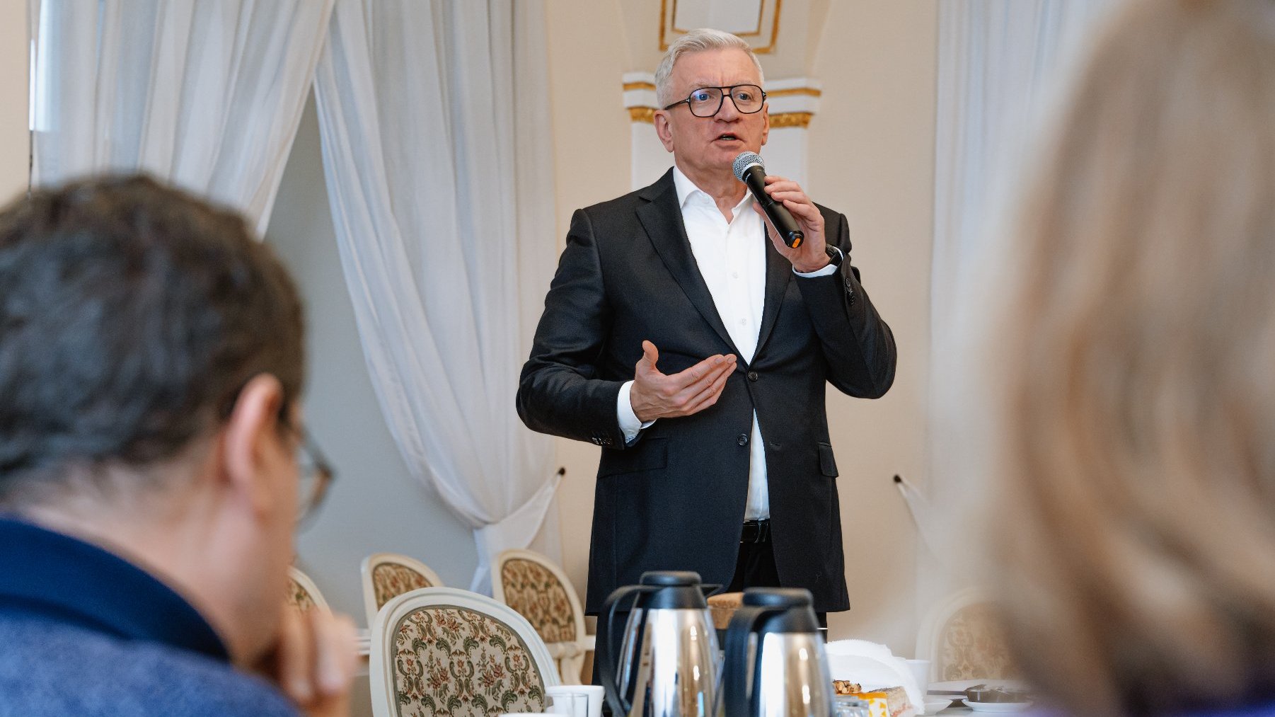 Prezydent Jacek Jaśkowiak w szarym garniturze. Mówi do mikrofonu i gestykuluje.