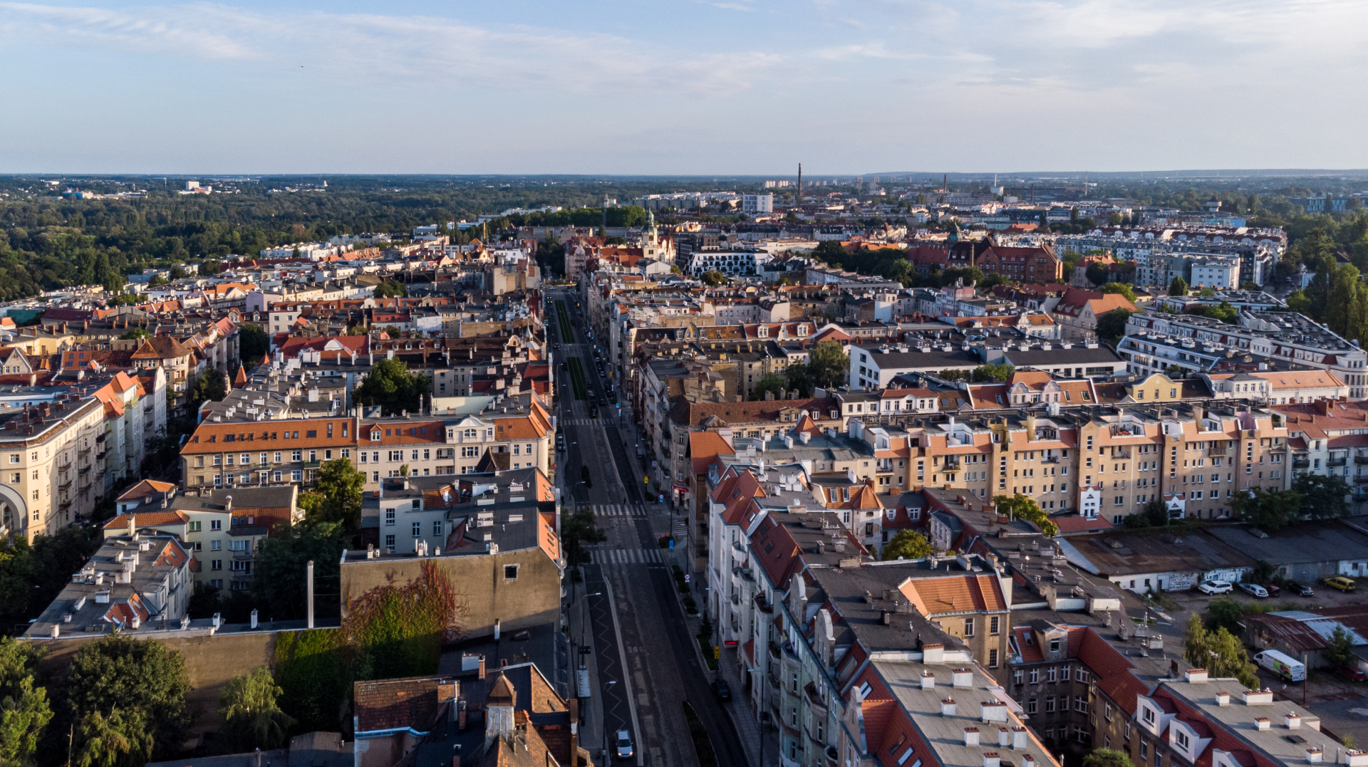 Zdjęcie przedstawia panoramę Poznania. W środku kadru widać jezdnię i chodniki otoczone gęstą zabudową. - grafika artykułu