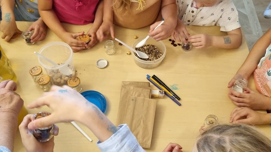 Dzieci uczestniczące w warsztatcie z pszczelarzem podczas wykonywania słoiczków z bakaliami i miodem