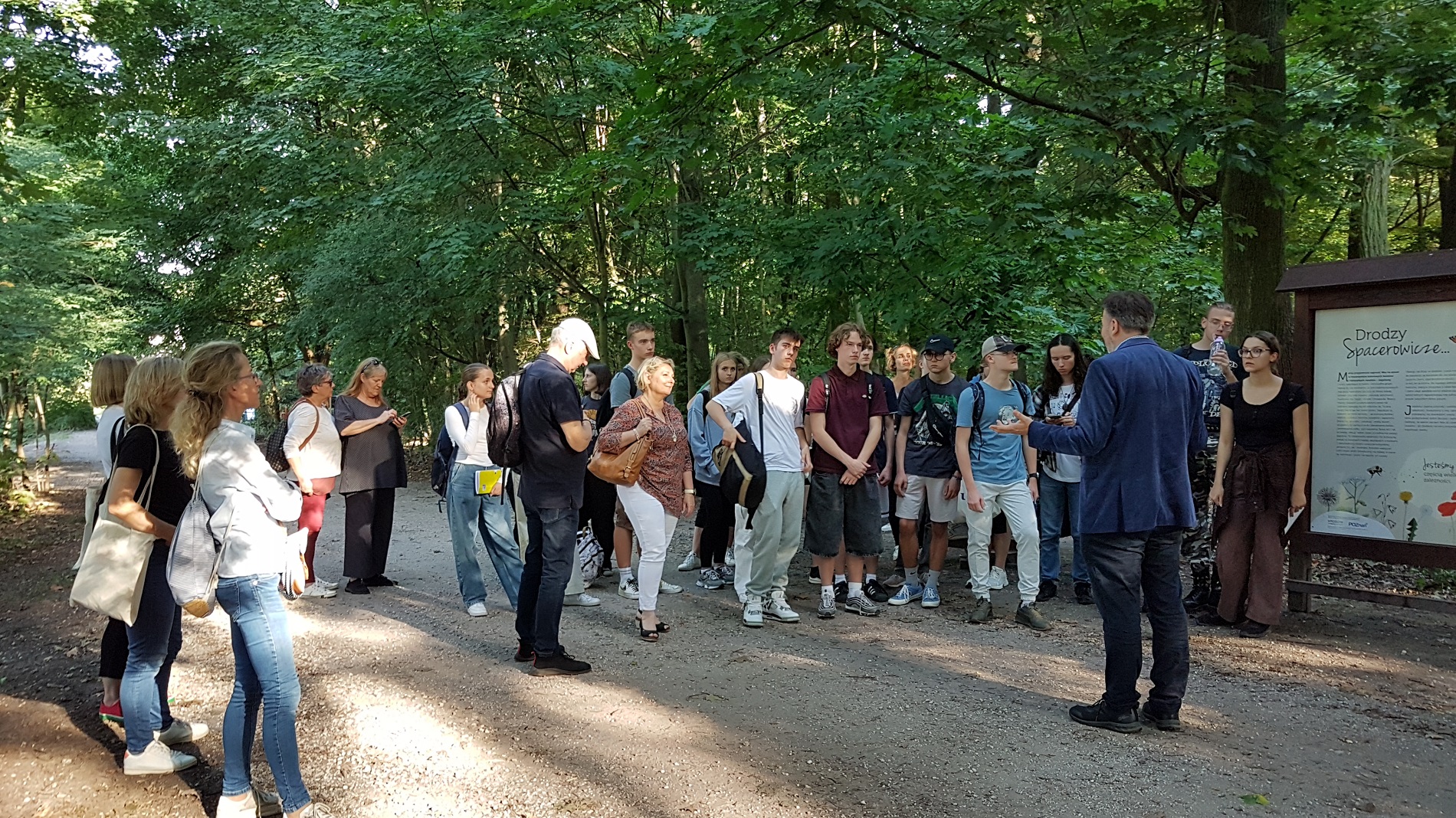 Grupa nauczycicieli i uczniów słuchająca prof. Sienkiewicza. - grafika artykułu