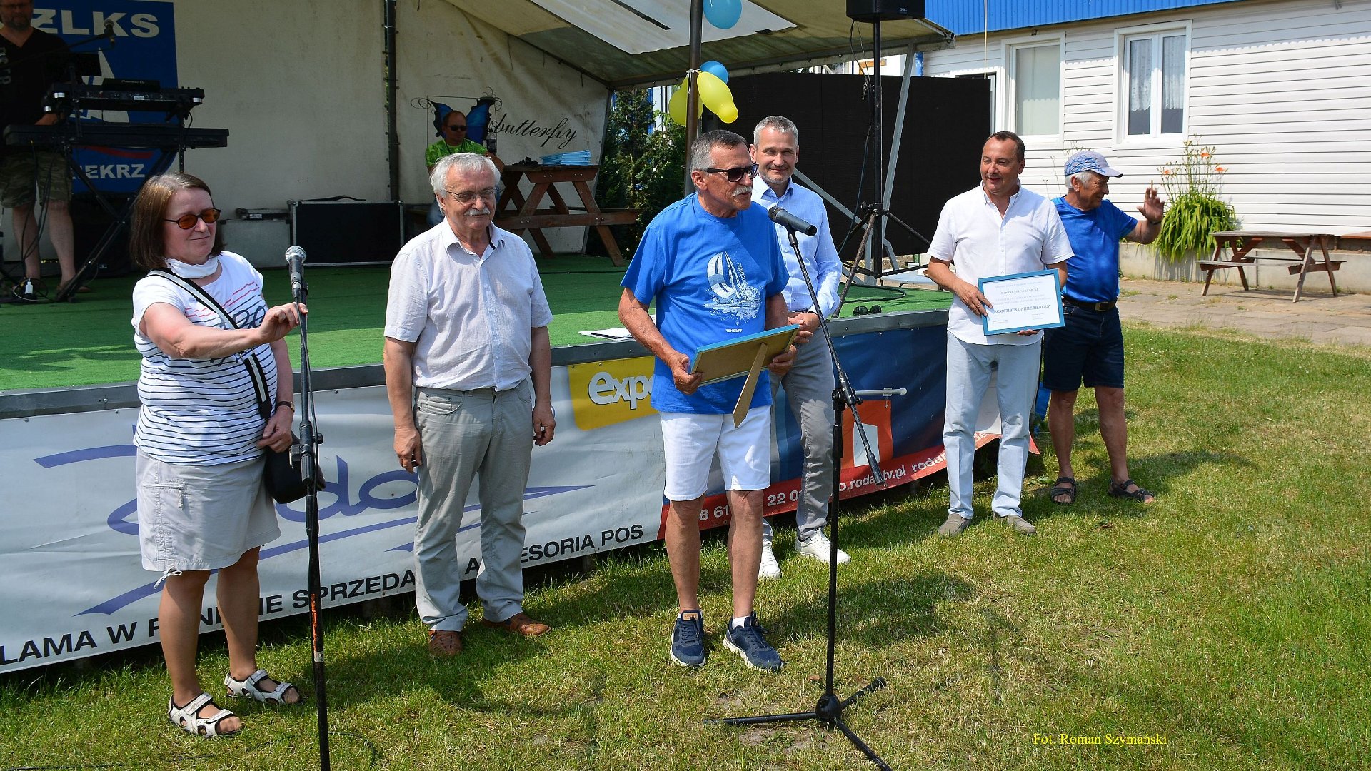 Wyjazdowe posiedzenie MRS (Kiekrz, 17.06.2021), na zdjęciu m.in. seniorzy, plener, stoją przy mikrofonach, w tle scena