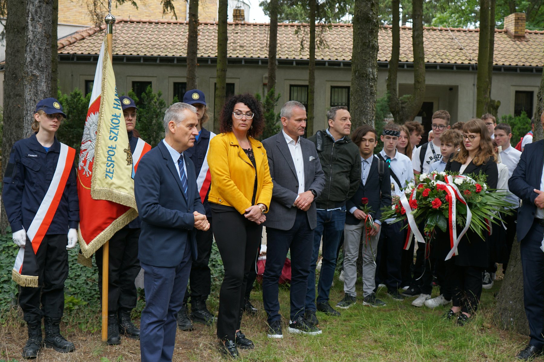 Zdjęcie przedstawia młodziedż i dorosłych na cmentarzu. - grafika artykułu