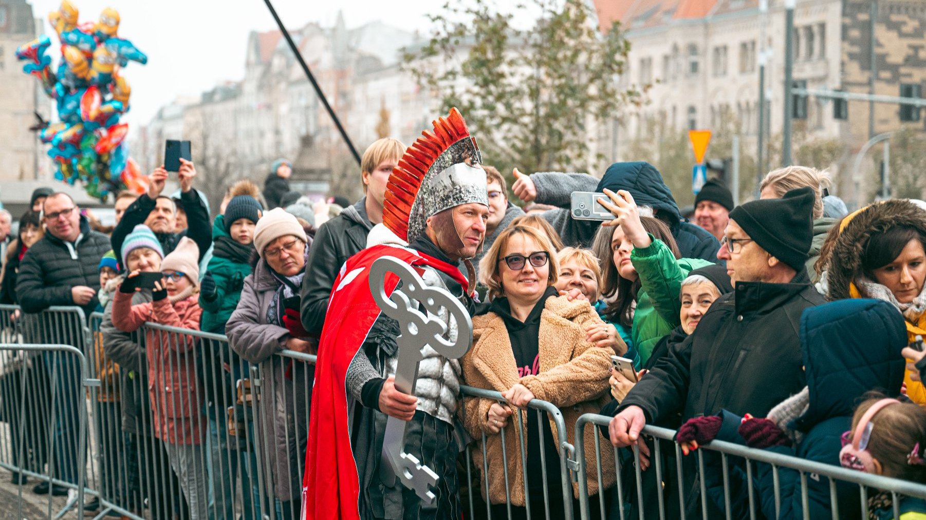 Postać przebrana za Świętego Marcina trzymające w ręce klucz do Miasta fotografuje się z ludźmi zgromadzonymi na centrum Poznania