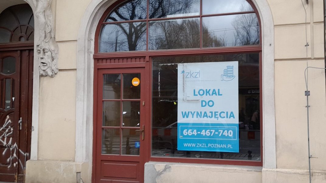 Zdjęcie przedstawia wejście do lokalu. Na szybie jest naklejony plakat z informacją, że ten lokal jest do wynajęcia.