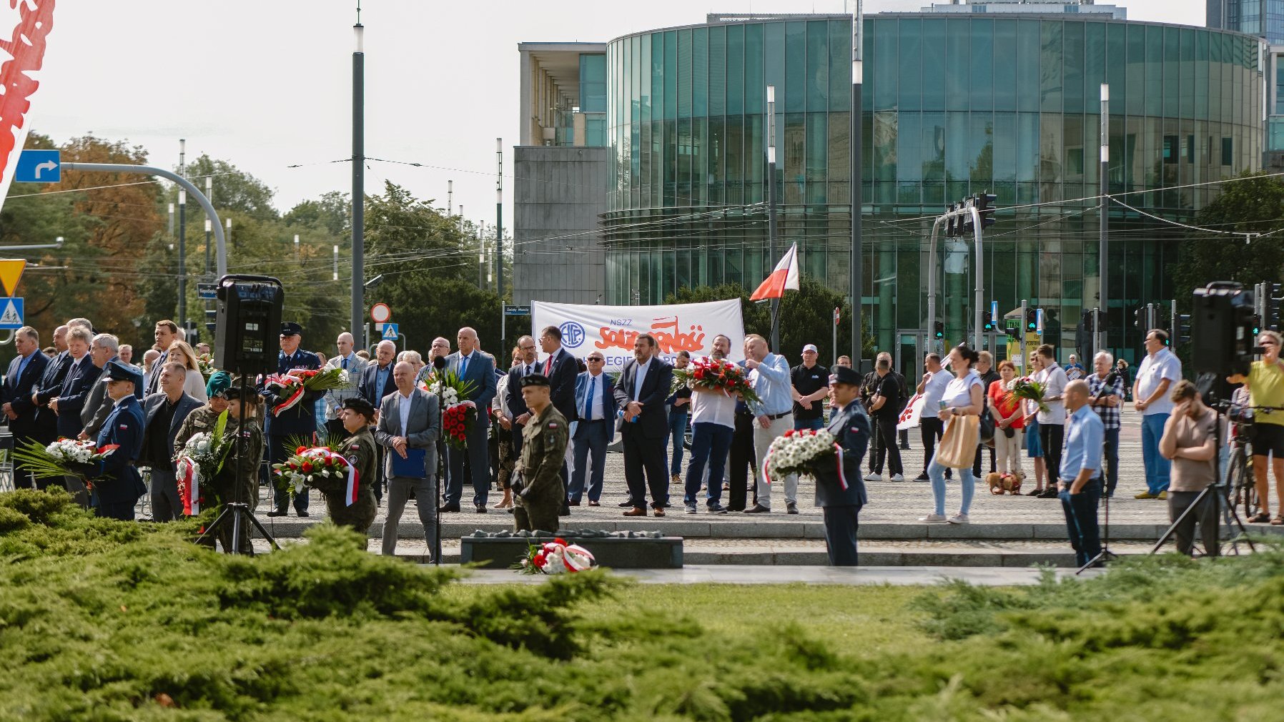 Zdjęcie przedstawia ludzi stojących na placu Mickiewicza.