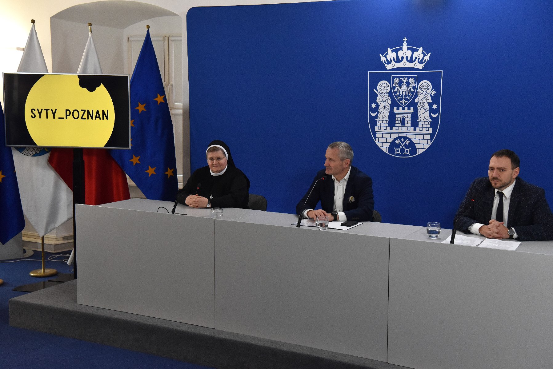 Na zdjeciu trzy osoby za stołem konferencyjnym, dwóch mężczyzn i zakonnica - grafika artykułu