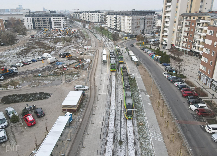 widok z lotu ptaka na trasę tramwajową, przystanek tramwajowy obustronny, wokół bloki mieszkalne, parkujące samochody, pora zimowa - grafika artykułu