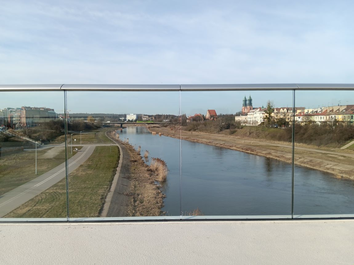 most nad rzeką za szklaną balustradą widok na rzekę, tereny zielone, budynki - grafika artykułu