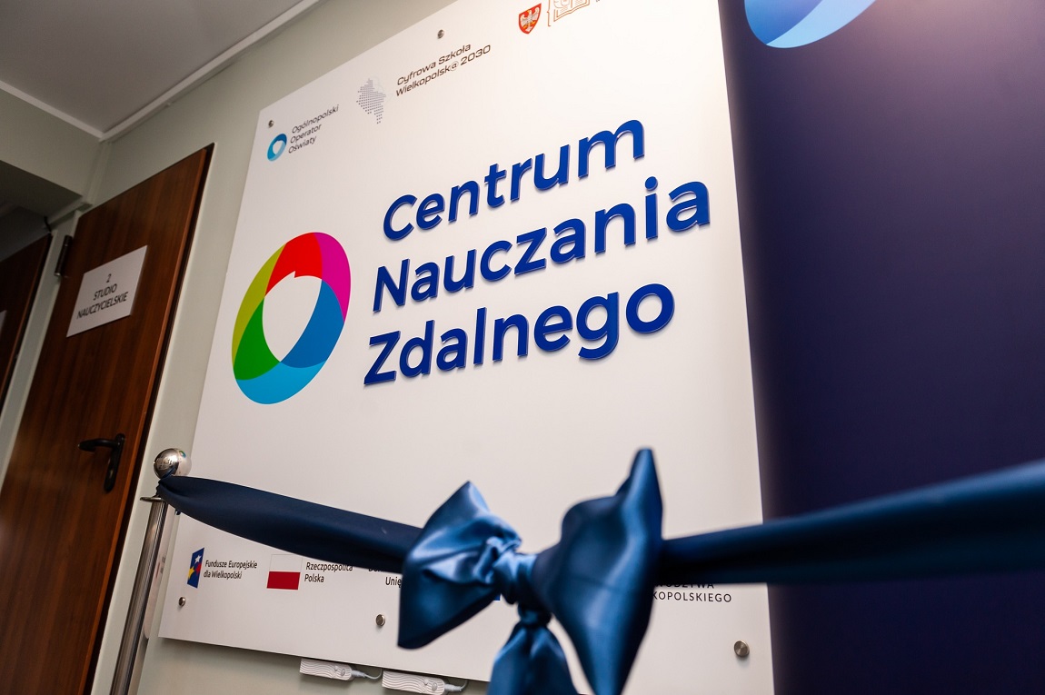 plansza z napisem Centrum Nauczania Zdalnego, przed nią stojaki z szarfą zawiązaną na kokradę - grafika artykułu