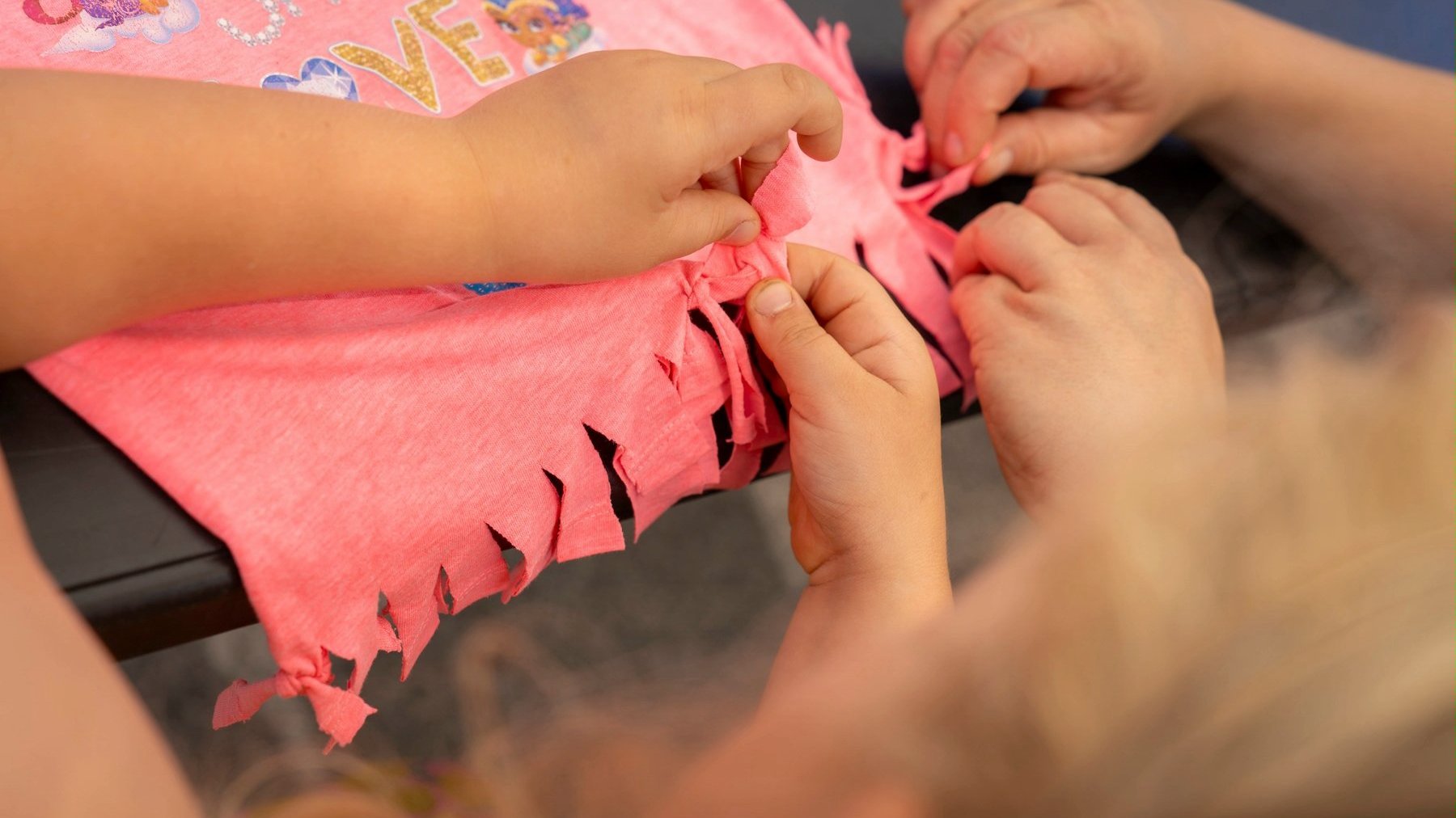 Dziecięce ręce pracują na różowej tkanine.
