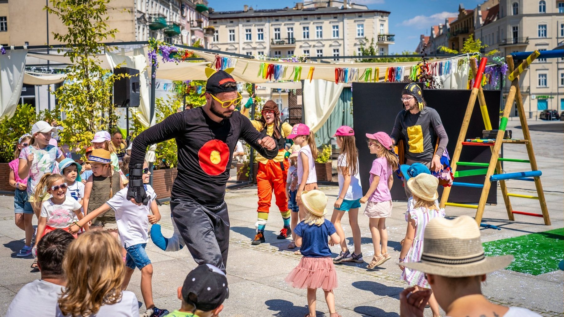 Zdjęcie, dzieci bawiące się na rynku razem z animatorem.