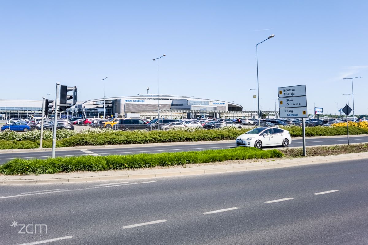 Zdjęcie od ul. Bukowskiej pokazujące parking, a w tle budynek lotniska - grafika artykułu