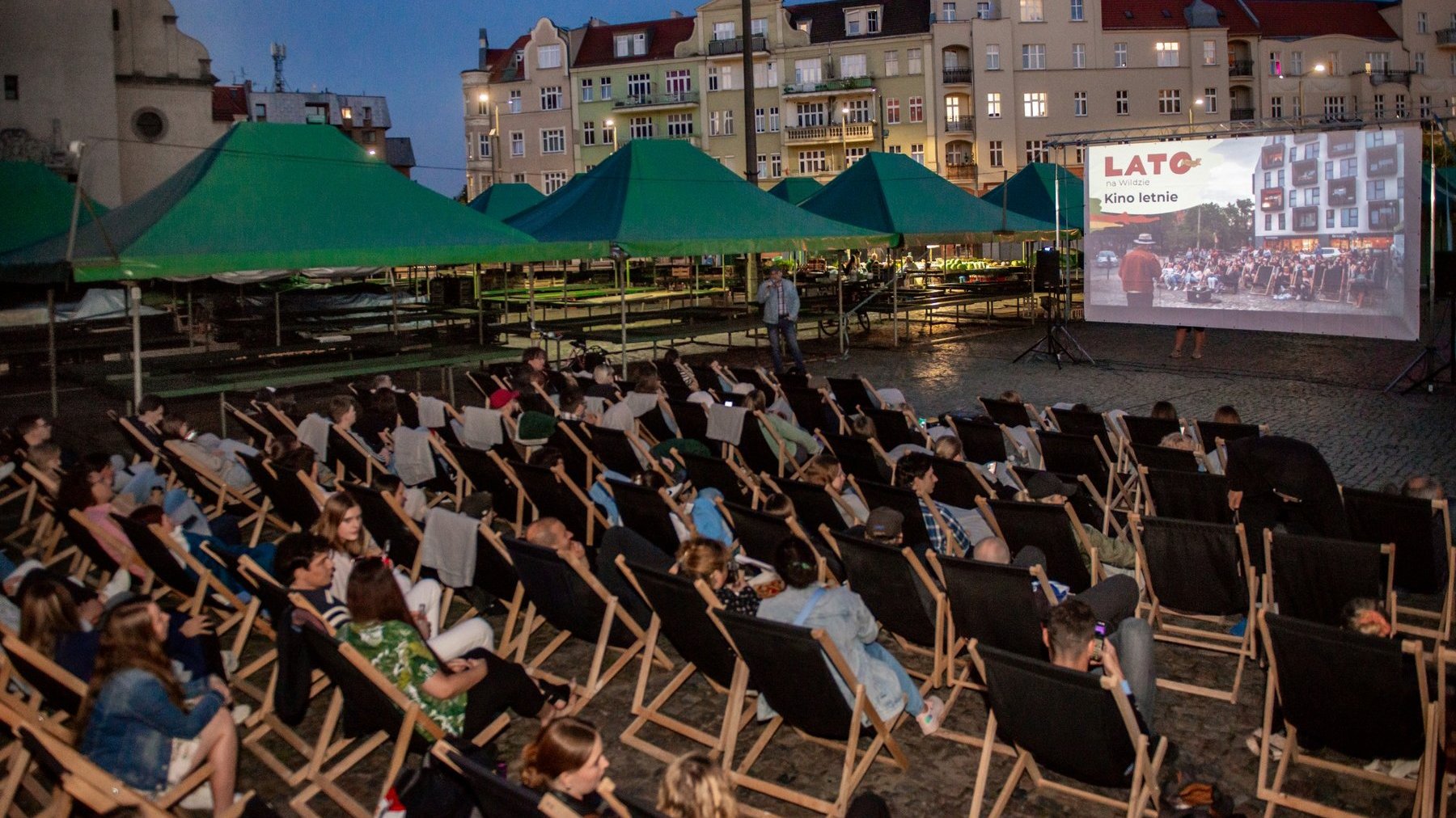 Na zdjęciu widać osoby siedzące na leżakach na rynku Wildeckim i oglądające film na ekrania