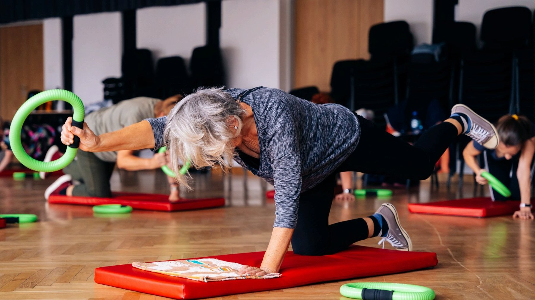 Zdjęcie przedstawia seniorkę wykonującą ćwiczenia na macie. - grafika artykułu