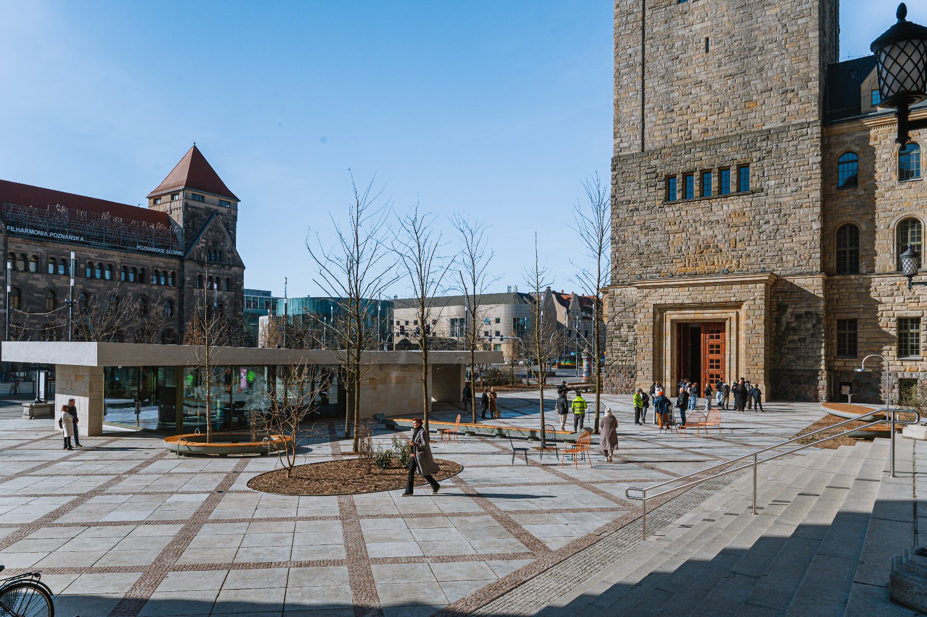 Nowa przestrzeń przed Centrum Kultury Zamek widać ławki, drzewa, nową kawiarnię - grafika artykułu