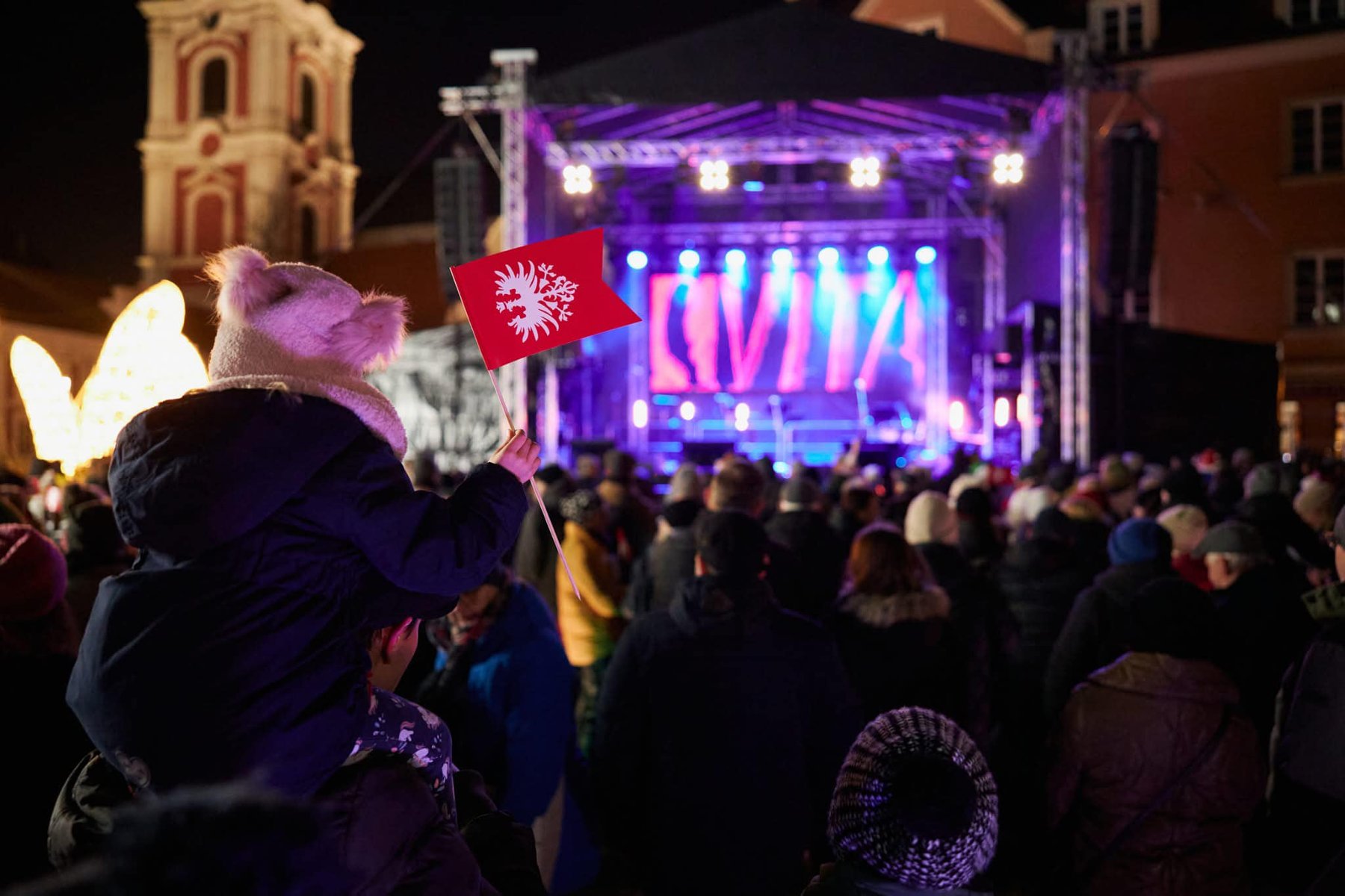 Zdjęcie z zeszłorocznego koncertu. W tle widać scenę na placu Kolegiackim a na pierwszym planie dziecko trzyma flagę powstańczą - grafika artykułu