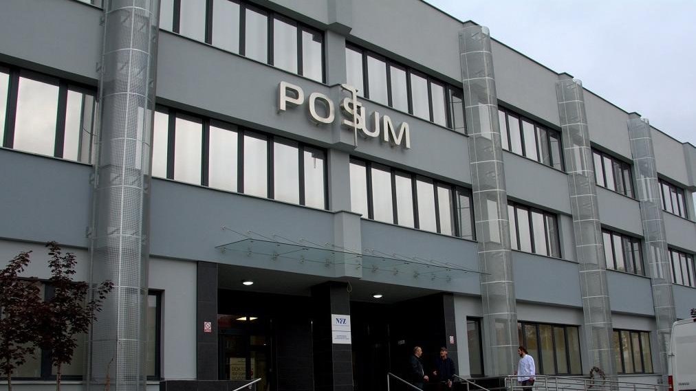 Fasada POSUM: nowoczesna, trzykondygnacyjna, szara, nad głównym wejściem napis "POSUM"