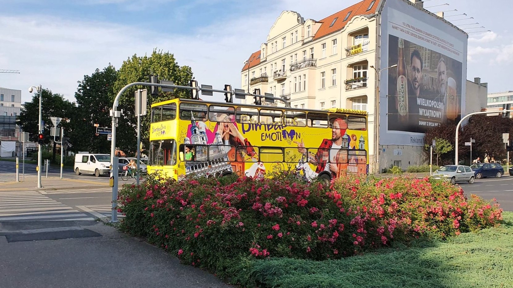 Na zdjęciu znajduje się żółty, turystyczny autobus, typu londyńskiego, jadący ulicą