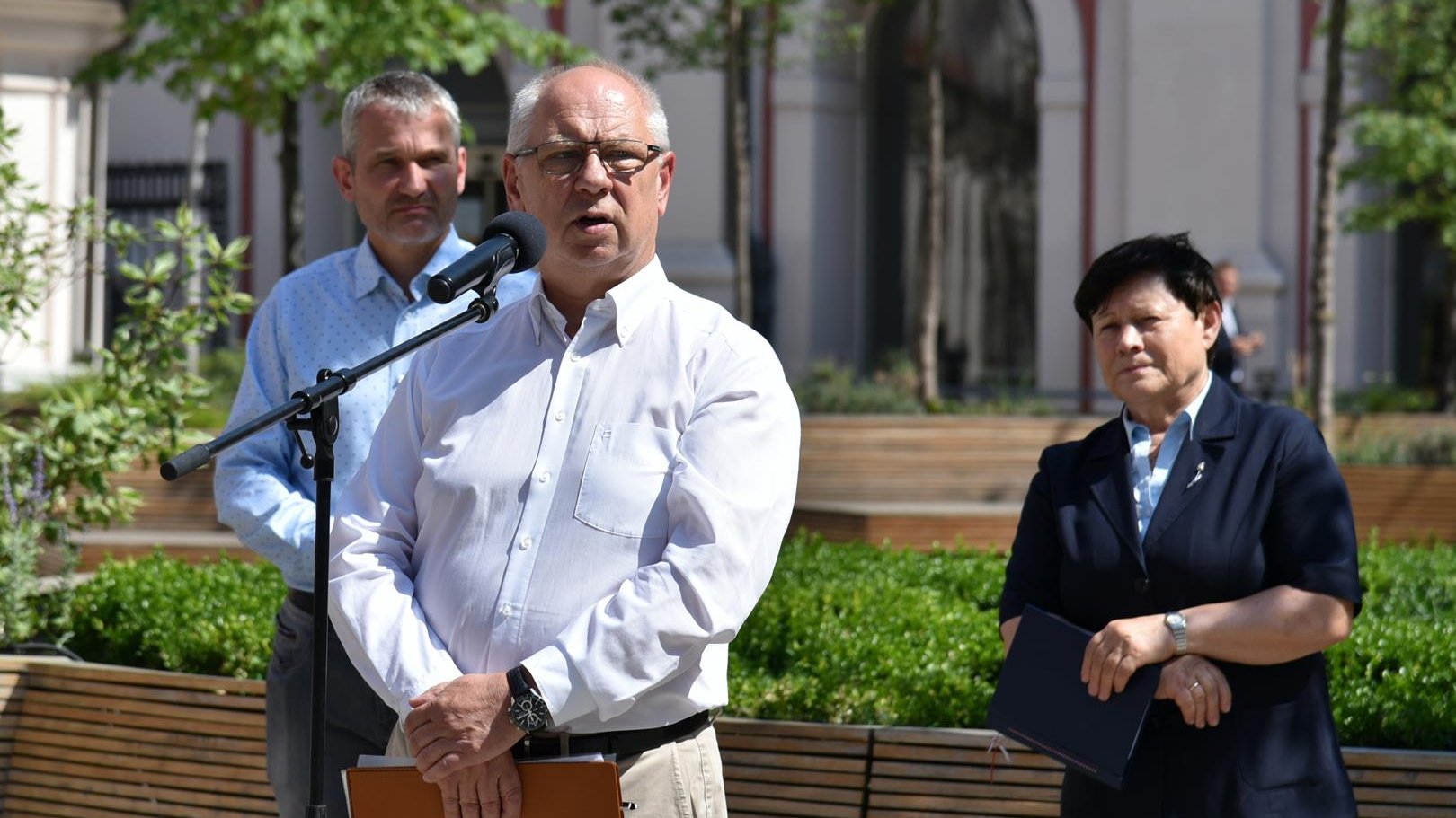 Aleksander Daniel, prezes Fundacji Wielkopolskie Wioślarstwo, stoi przy mikrofonie na dziedzińcu urzędu. Za nim Jędrzej Solarski, zastępca prezydenta Poznania oraz Ewa Bąk, dyrektor Wydziału Sportu UMP