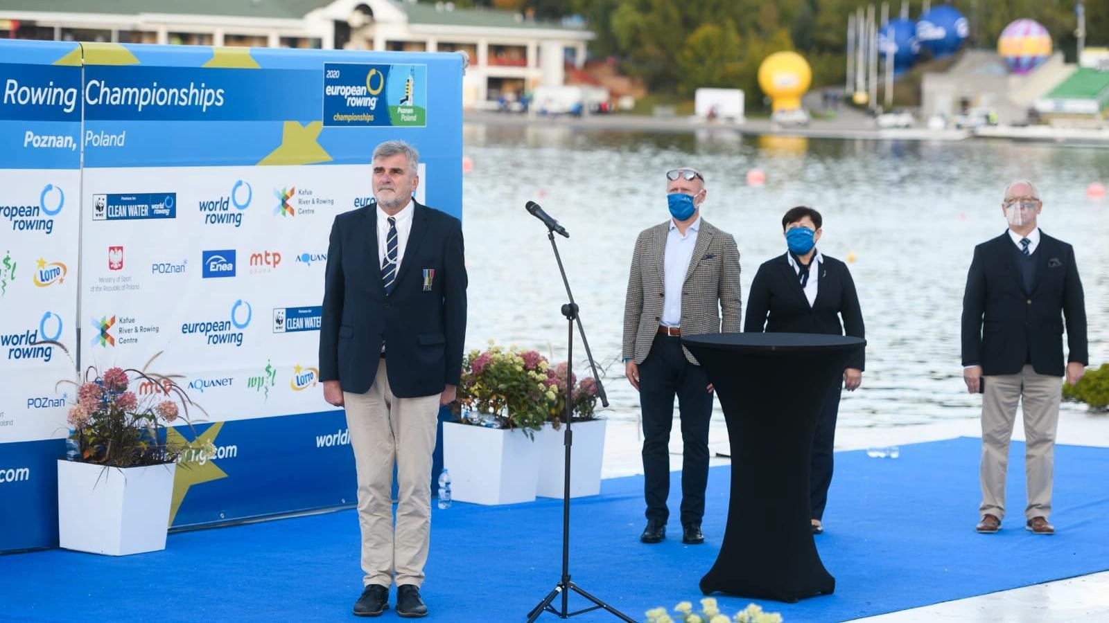 Zdjęcie przedstawia przedstawicieli instytucji organizujących zawody, w tym Miasta Poznania, na niebieskim dywanie, na tle jeziora Maltańskiego.