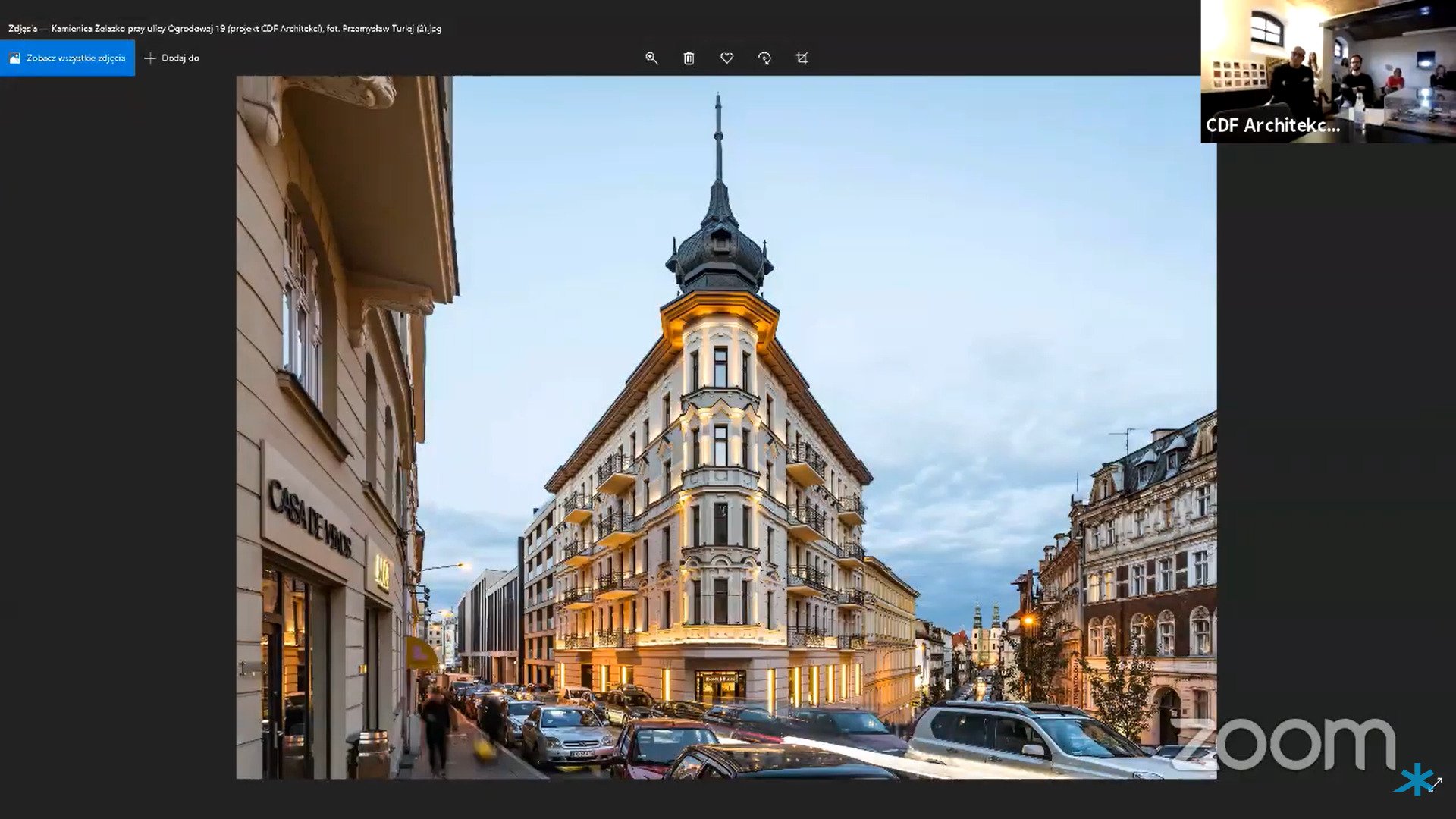 Na zdjęciu zrzut ekranu z platformy konferencyjnej online. W głównym oknie fotografia nagrodzonej kamienicy. W małym oknie w rogu ekranu - przedstawiciele pracowni CDF Architekci.