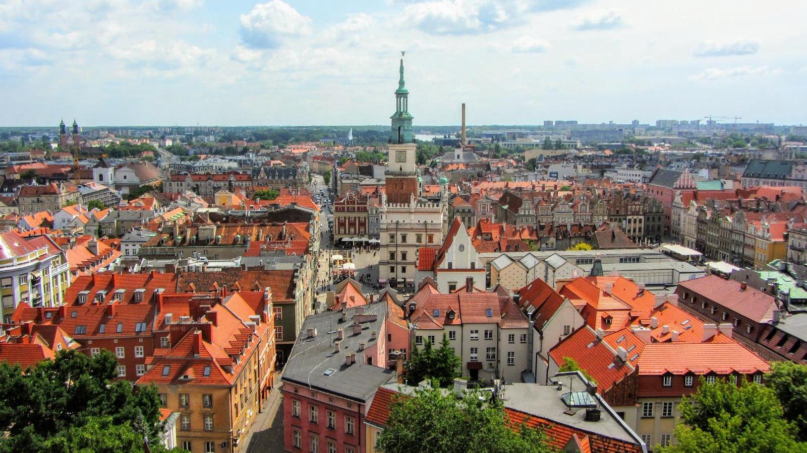 Zdjęcie przedstawia panoramę Poznania z lotu ptaka, w centrum Ratusz i dachy kamienic - grafika artykułu